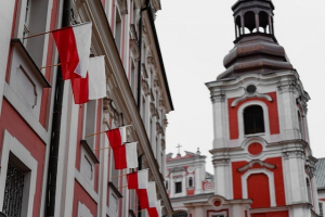 Polnische Flaggen ans Häuserfassaden. Im Hintergrunnd Glockenturm.