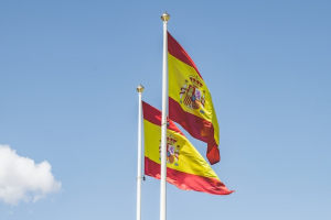 Zwei spanische Flaggen vor blauem Himmel.