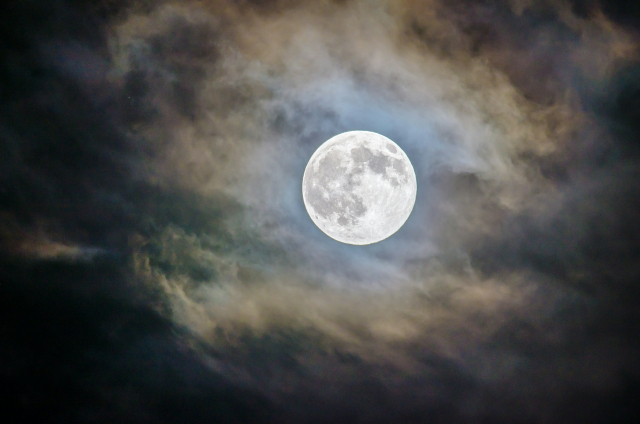 Nachthimmel mit Vollmond, umgeben von Wolken.